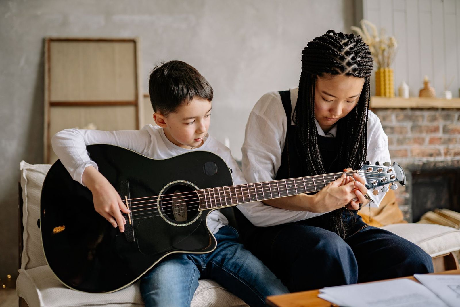 Kind lernt Akustikgitarre mit Anleitung eines Erwachsenen