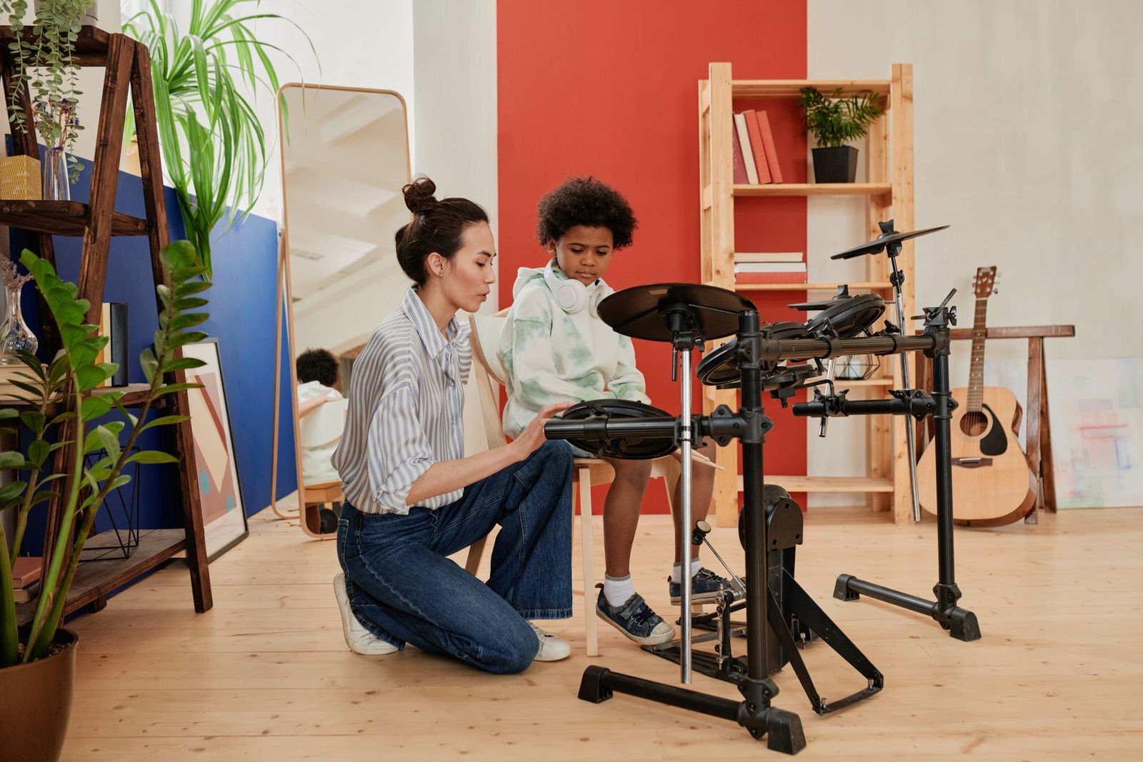 Musiklehrerin leitet ein Kind am elektronischen Schlagzeug an